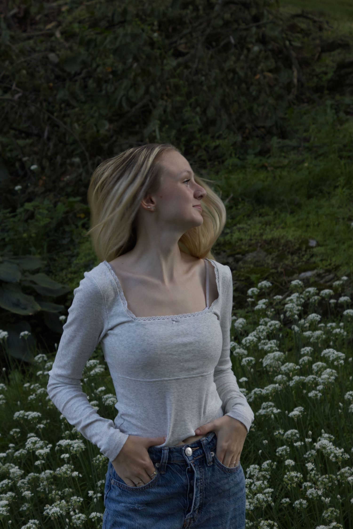 A young woman looks to the right, while her hair flairs in the air.