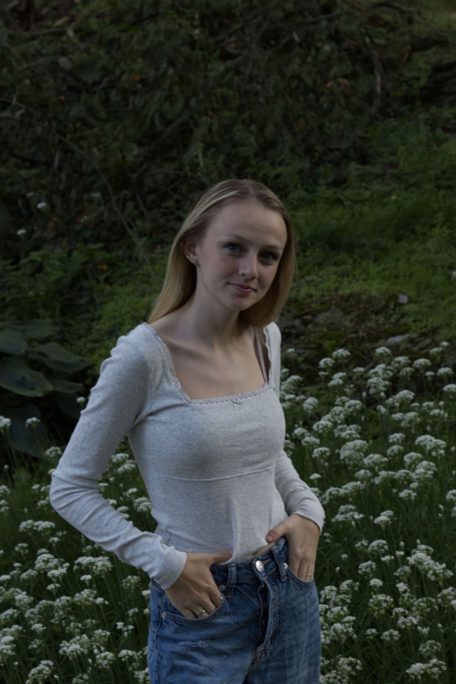 A young woman looks directly at the camera while her hands rest on her beltline.