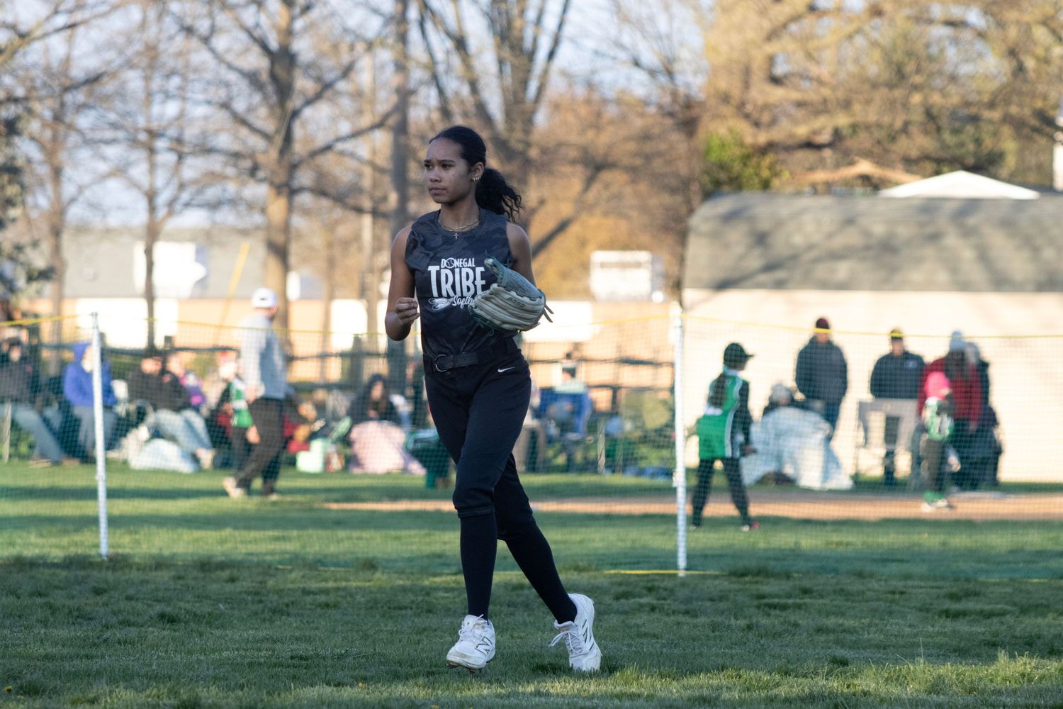 A softball player is walking quickly towards the infield.