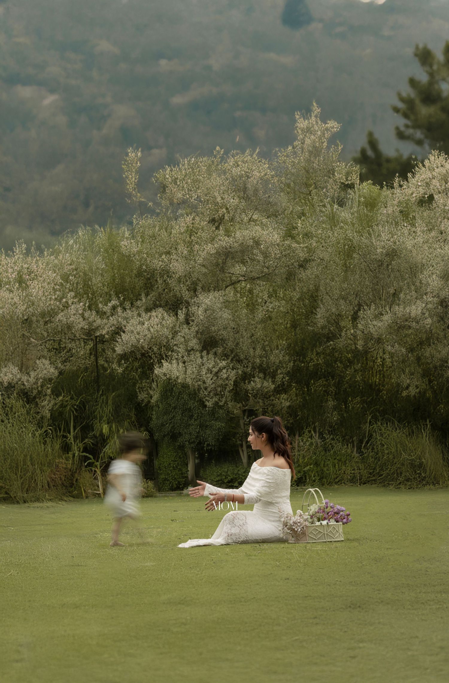 Two figures on a grassy field with blooming trees in the background during golden hour.