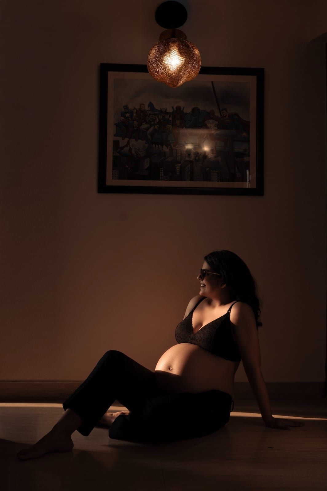 Moody maternity boudoir photo with dramatic lighting and pendant lamp.