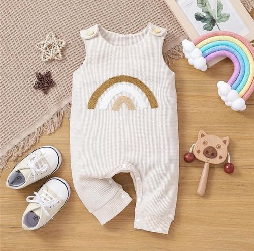 White baby outfit with rainbow design displayed alongside shoes and accessories.