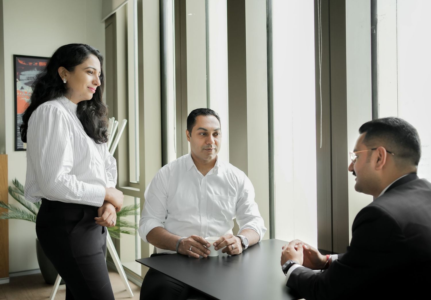 Professional colleagues having a business discussion in a modern office hallway.