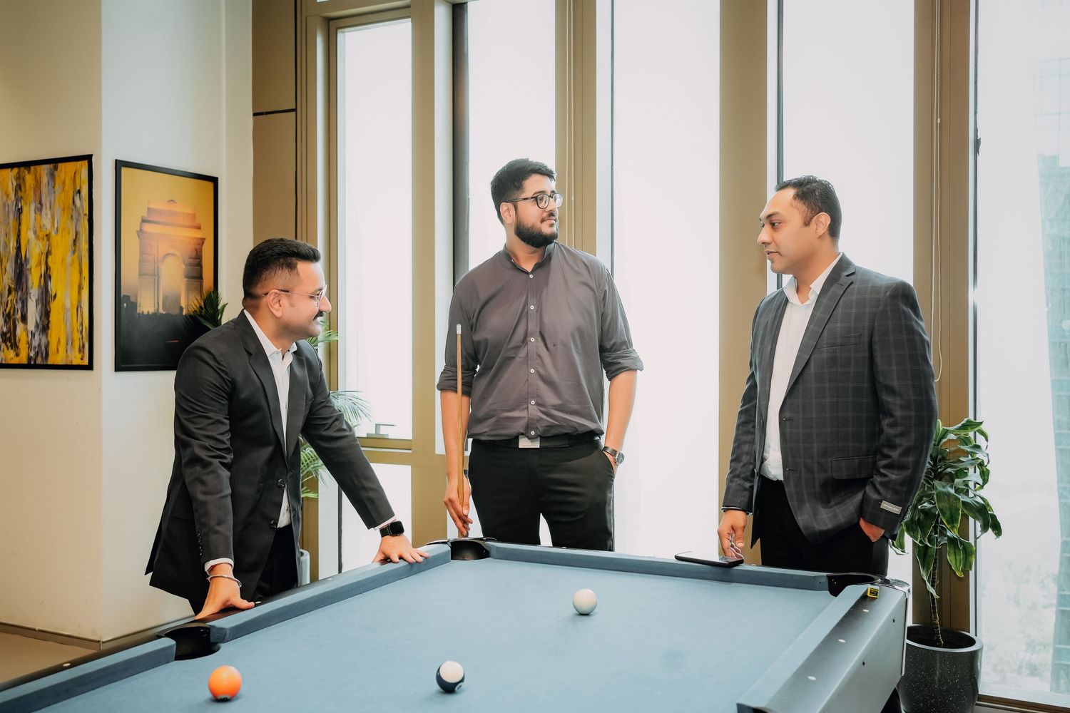 Business professionals gather in a modern office hallway for informal discussion.