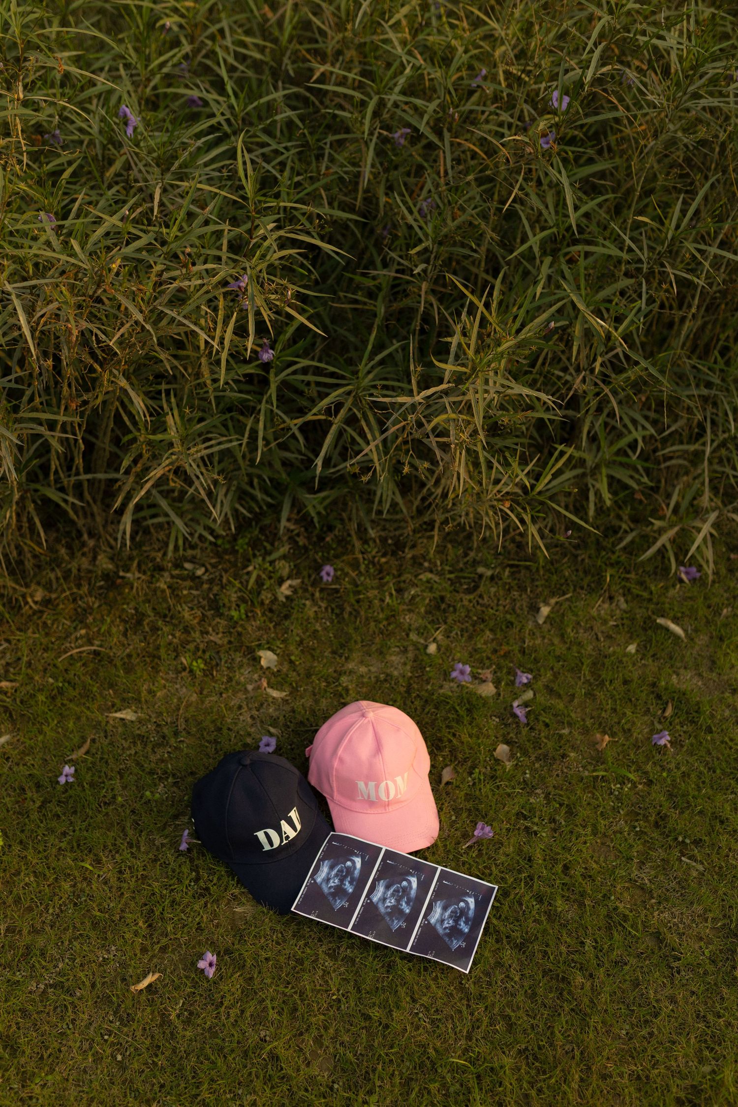 A sequence of four photos showing baseball caps and an ultrasound photo arranged on grass in a pregnancy announcement style.