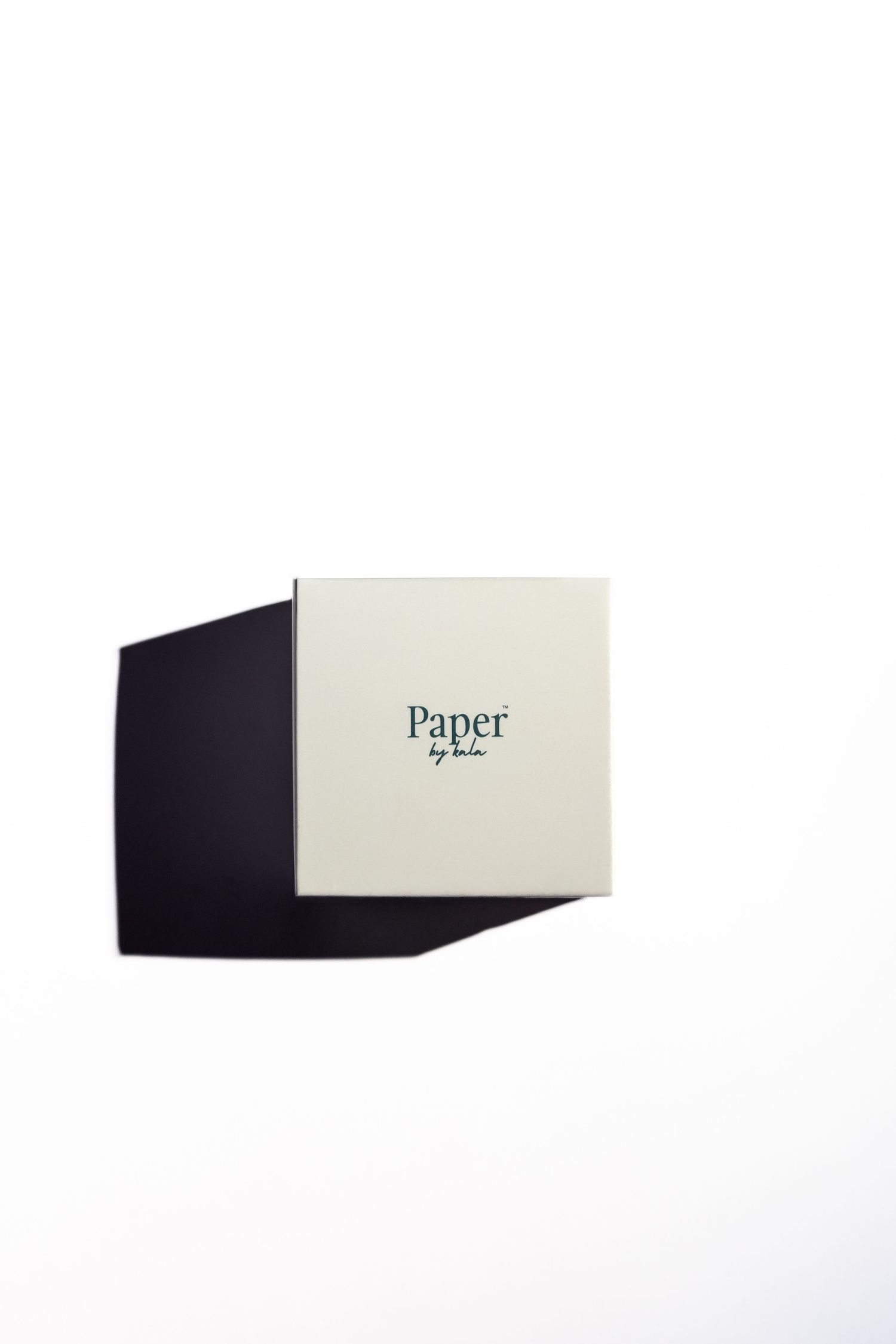 Cream square gift box with 'Paper by Lulu' printed in dark green, casting a dark angular shadow on a clean white background.