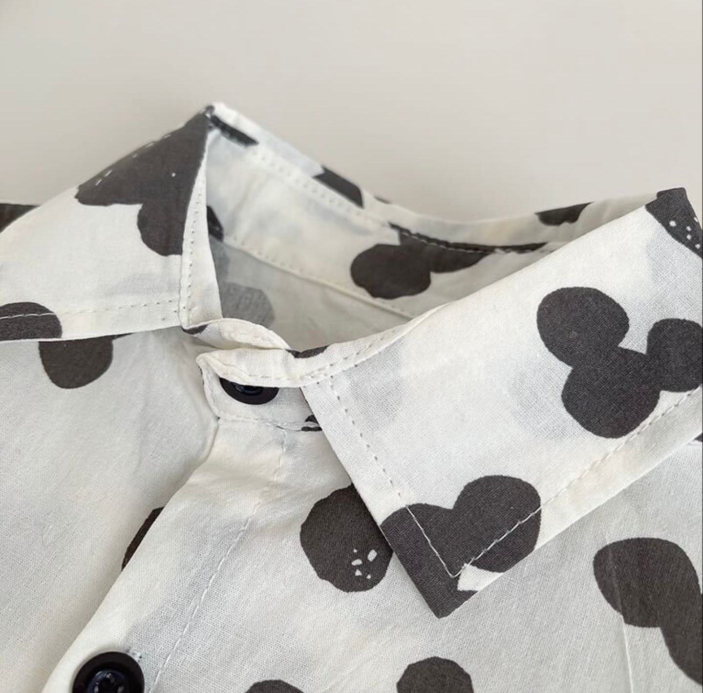 Black and white polka dot patterned fabric with pleated details shown in close-up view.