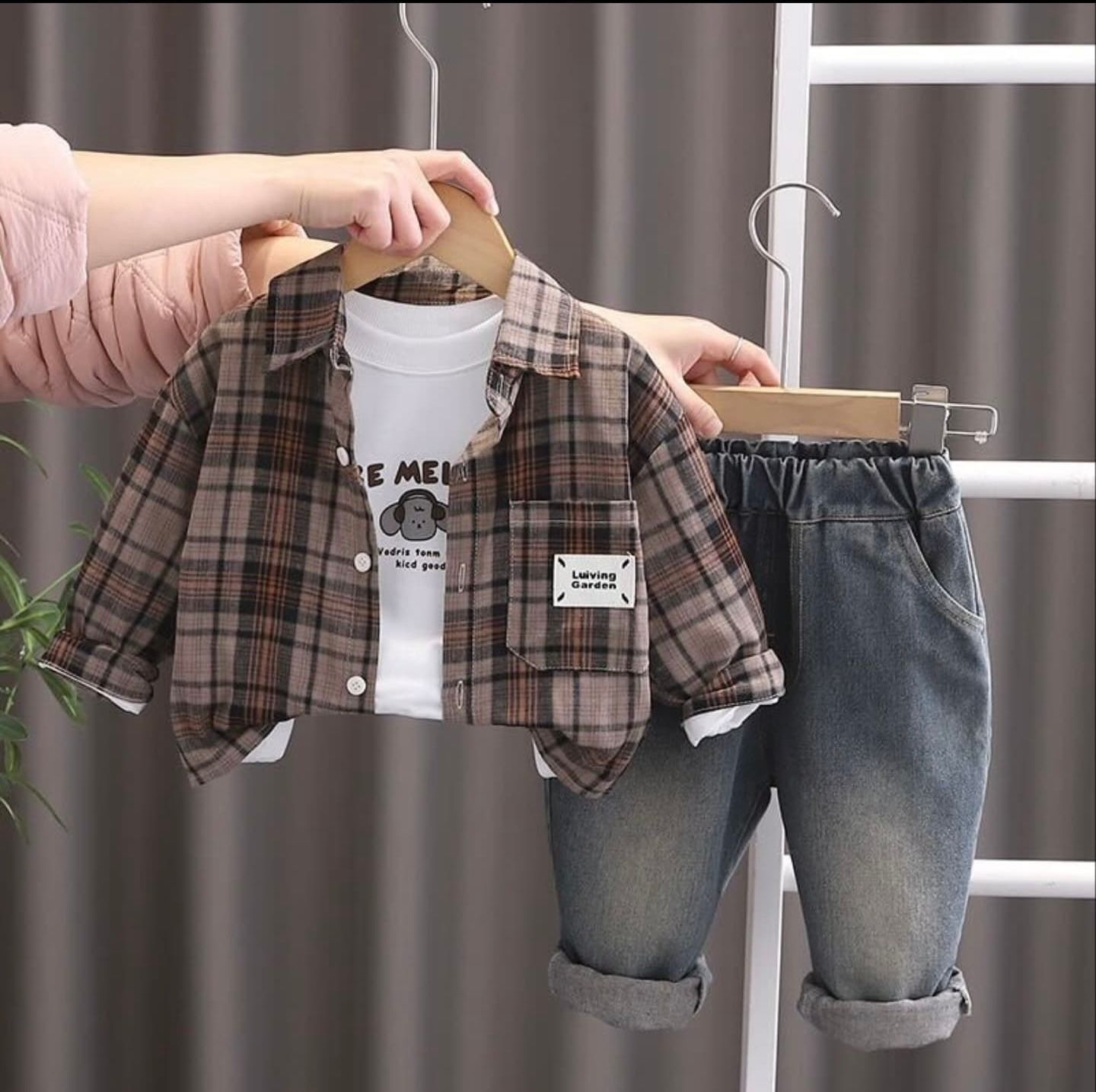 Person wearing plaid flannel shirt and jeans holding a reusable coffee tumbler in casual everyday style.