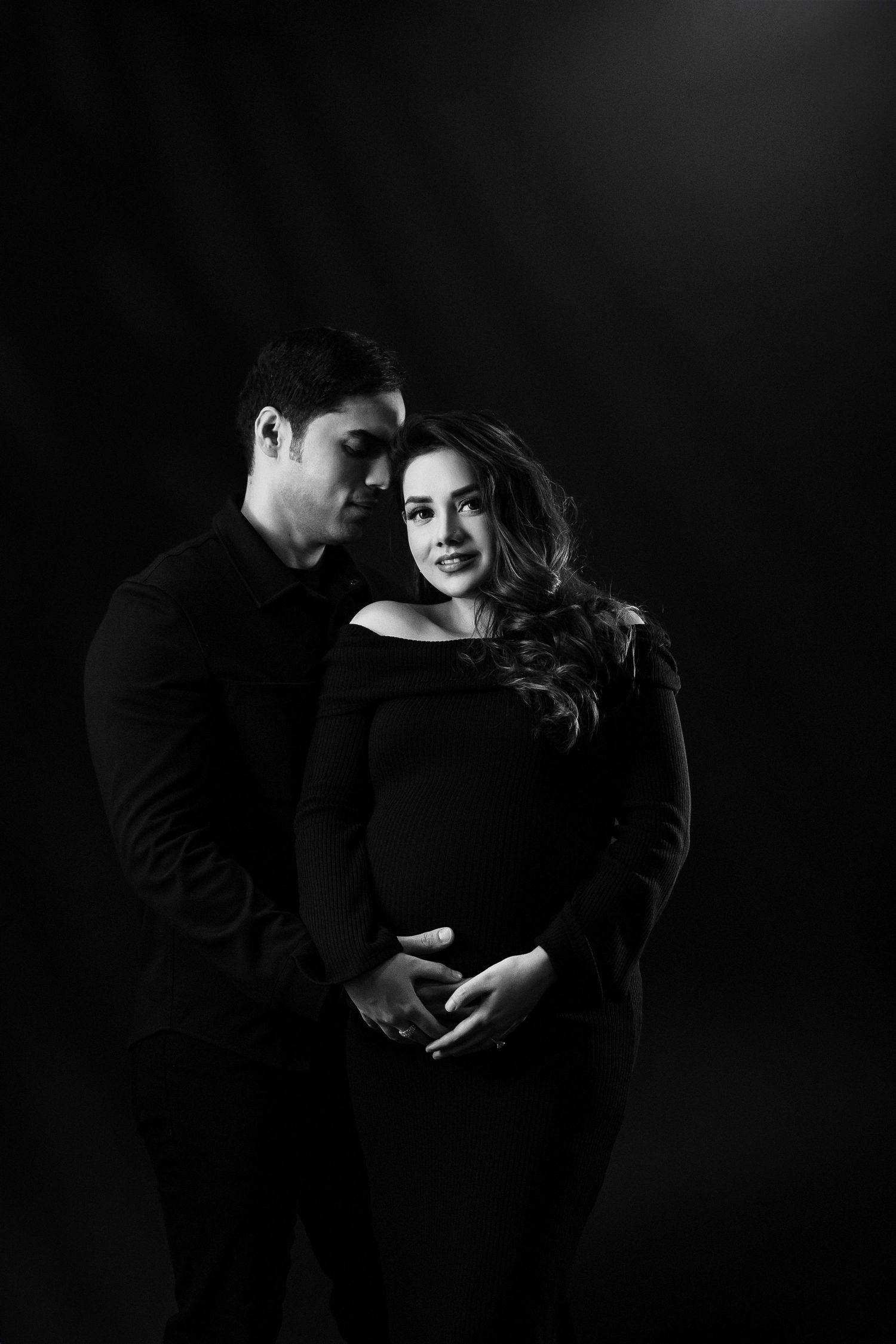 Intimate black and white maternity portraits with dramatic shadows.