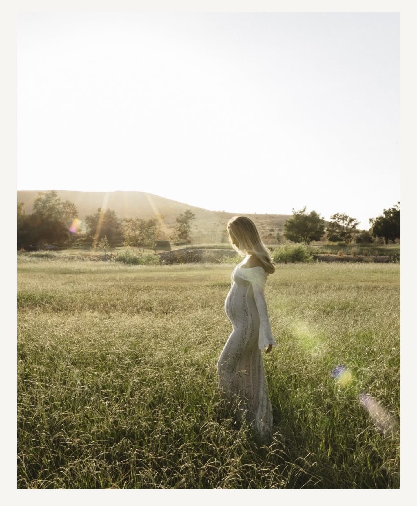 Dreamy outdoor maternity photography session in a meadow at sunset.