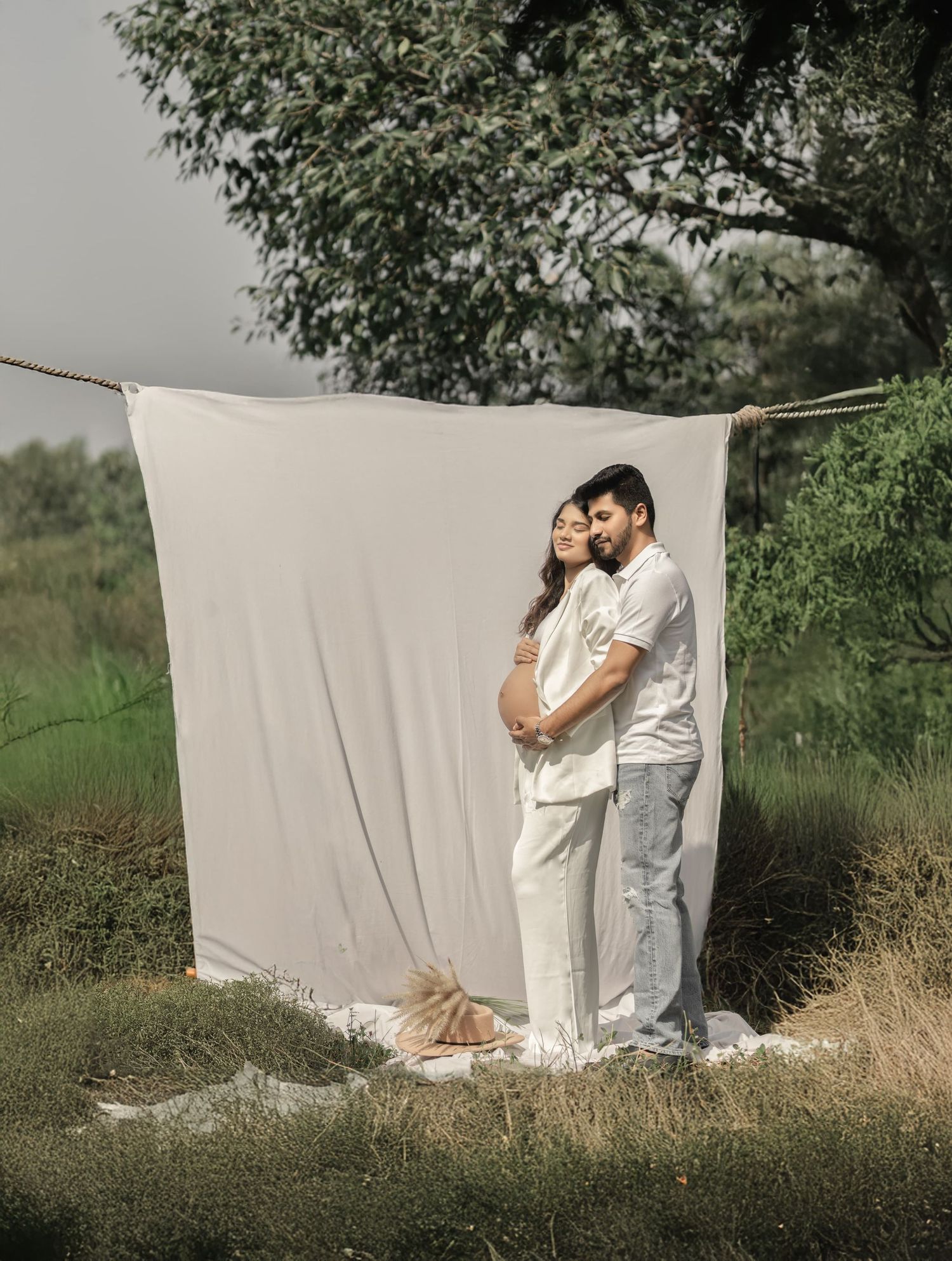 Outdoor couple's photoshoot against white backdrop with natural greenery.