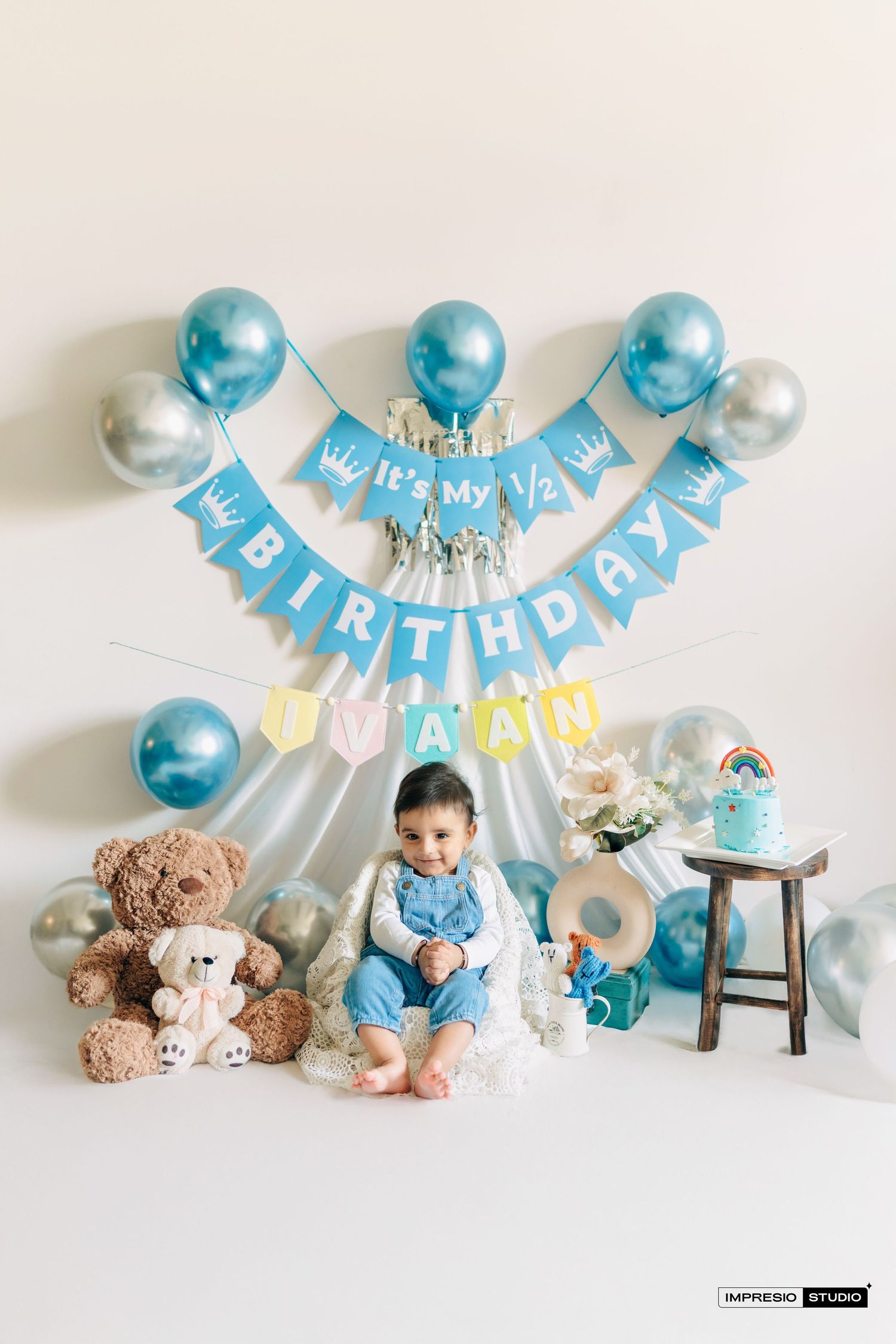 Baby's first birthday setup with blue and white decorations, teddy bears, and a small wooden chair.