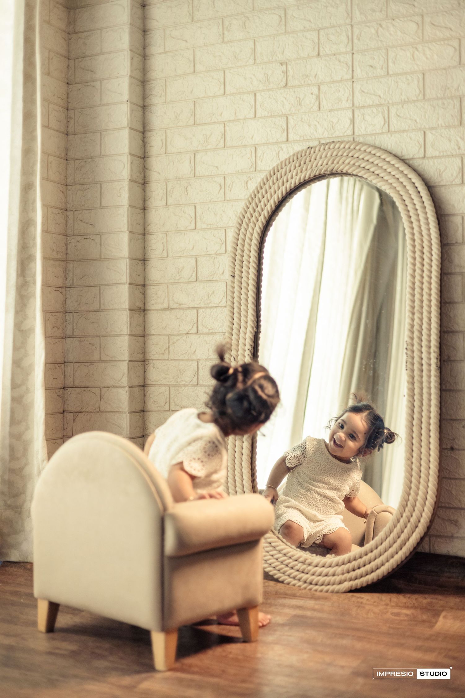 A series of five artistic photos showing a figure resting on a small cream-colored chaise lounge next to an oval mirror.
