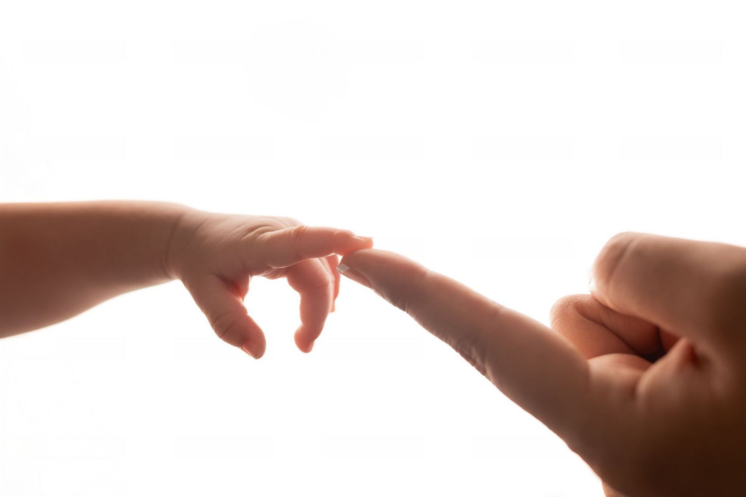 A small child's finger gently touching an adult's fingertip against a white background.