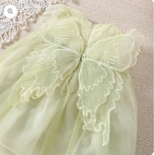 Close-up of mint green butterfly bow detail on dress fabric.