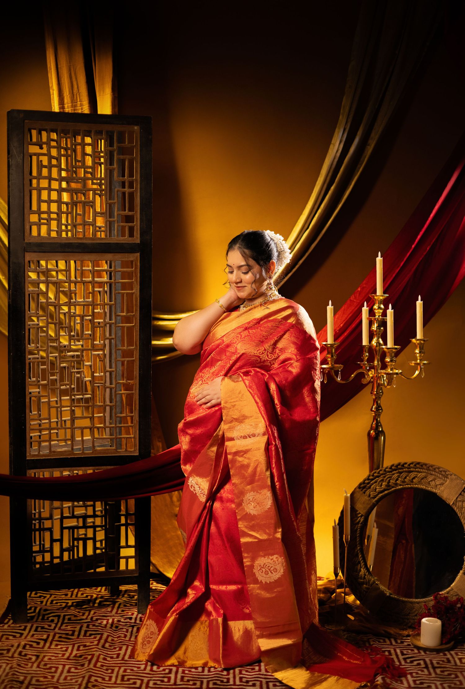 A figure in a flowing red and gold silk kimono poses gracefully in a dimly lit traditional Asian-inspired room with lanterns.