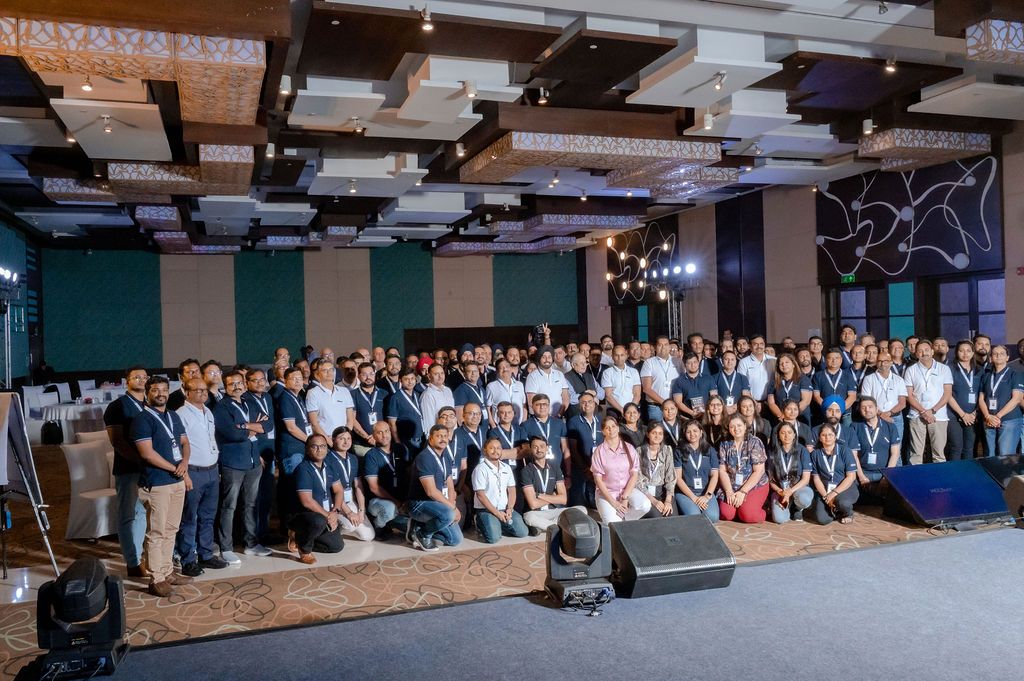 Large panoramic view of a crowded conference room with attendees seated in rows facing a presentation area.
