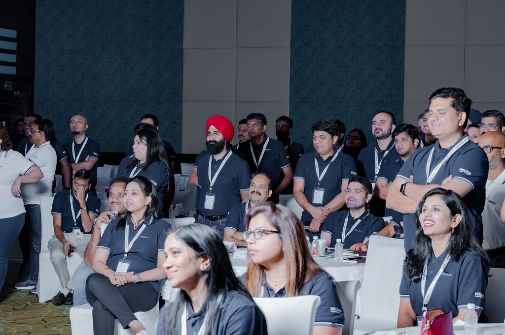 Business conference attendees seated at tables listen attentively during a professional presentation or seminar.