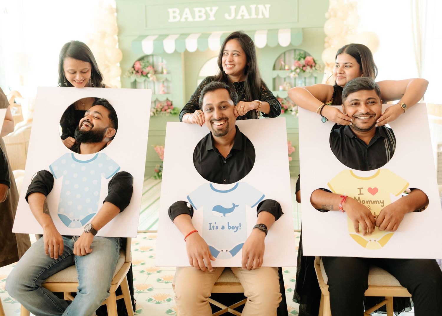 Group of friends posing with baby shower cutout boards at a Baby Jain its a boy celebration party.