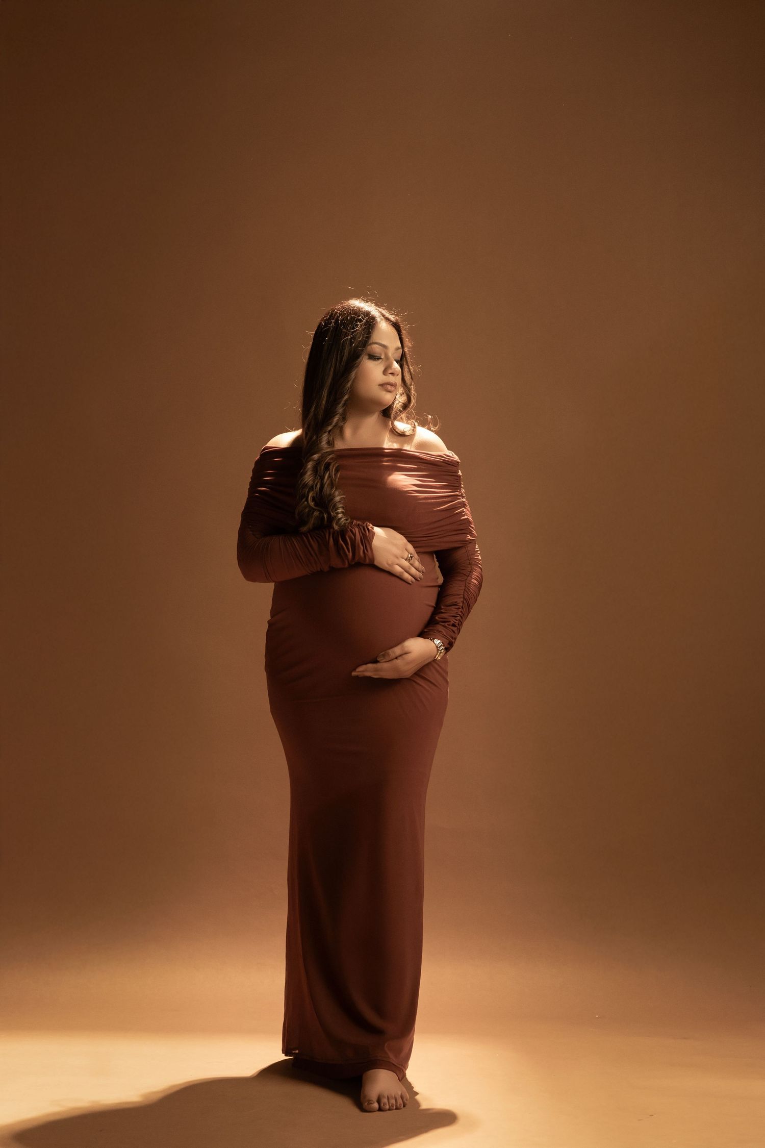Artistic maternity photos in warm brown tones showing gentle poses and soft lighting.