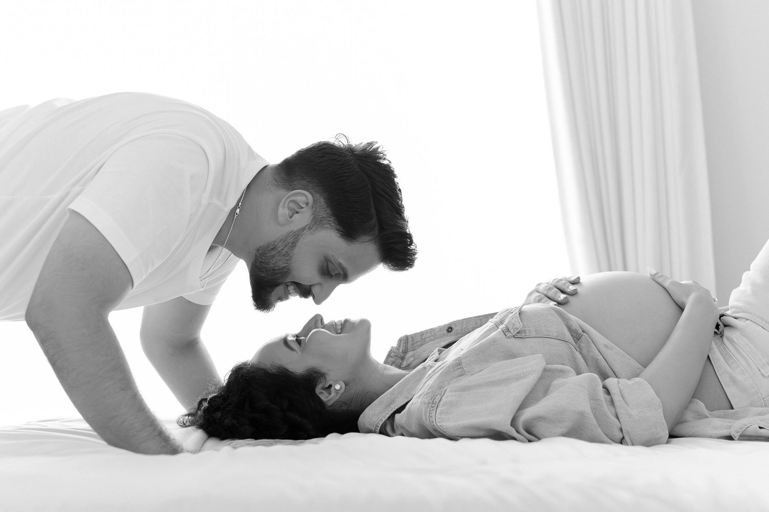 A sequence of intimate black and white photos showing a couple embracing in white sheets on a bed.