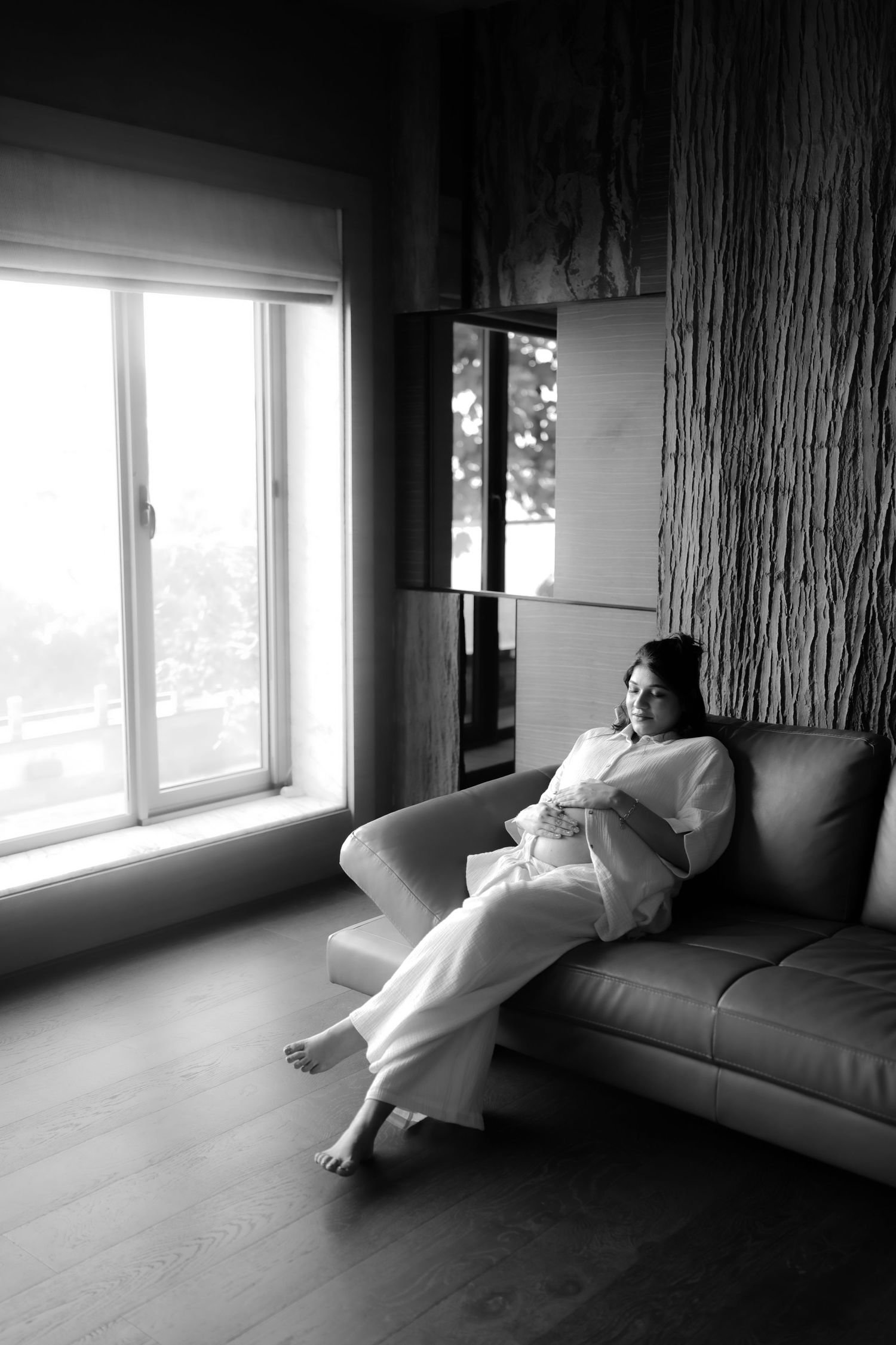 A series of black and white photos showing a figure reclining on a couch near a bright window.