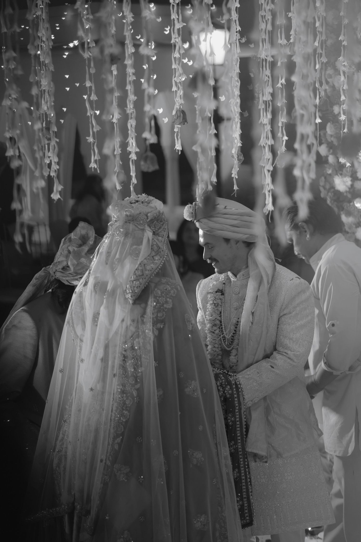 Black and white photo series showing people dancing in a formal setting with hanging decorative lights and crystals.
