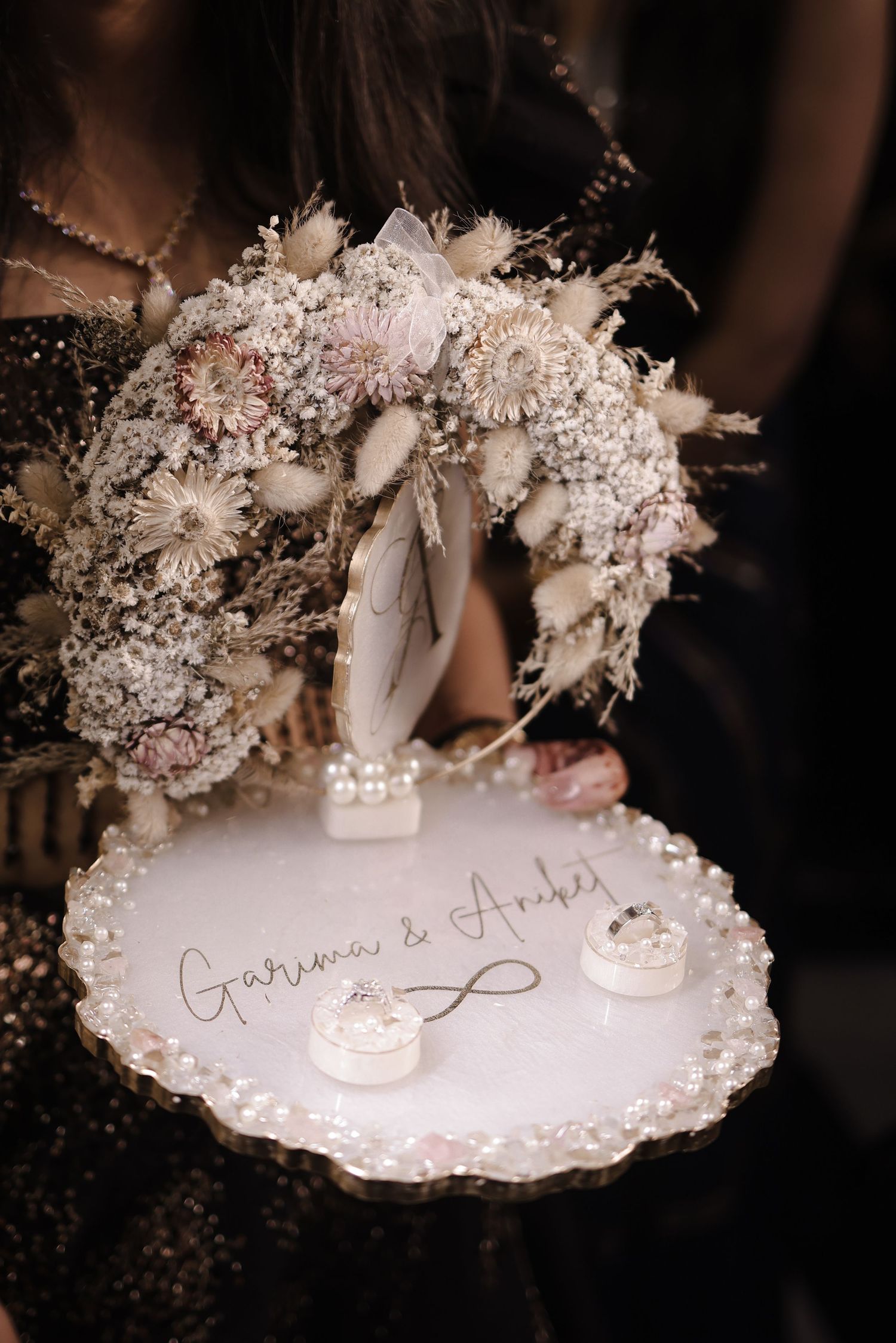 A delicate dried floral bouquet and decorative plate with elegant calligraphy writing displayed at a wedding celebration.