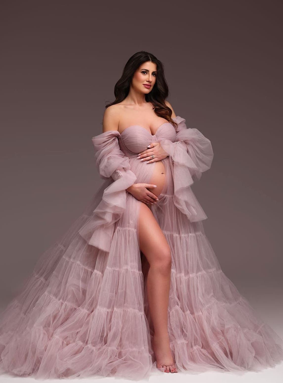 Ethereal pink ruffled maternity gown photographed against neutral background.