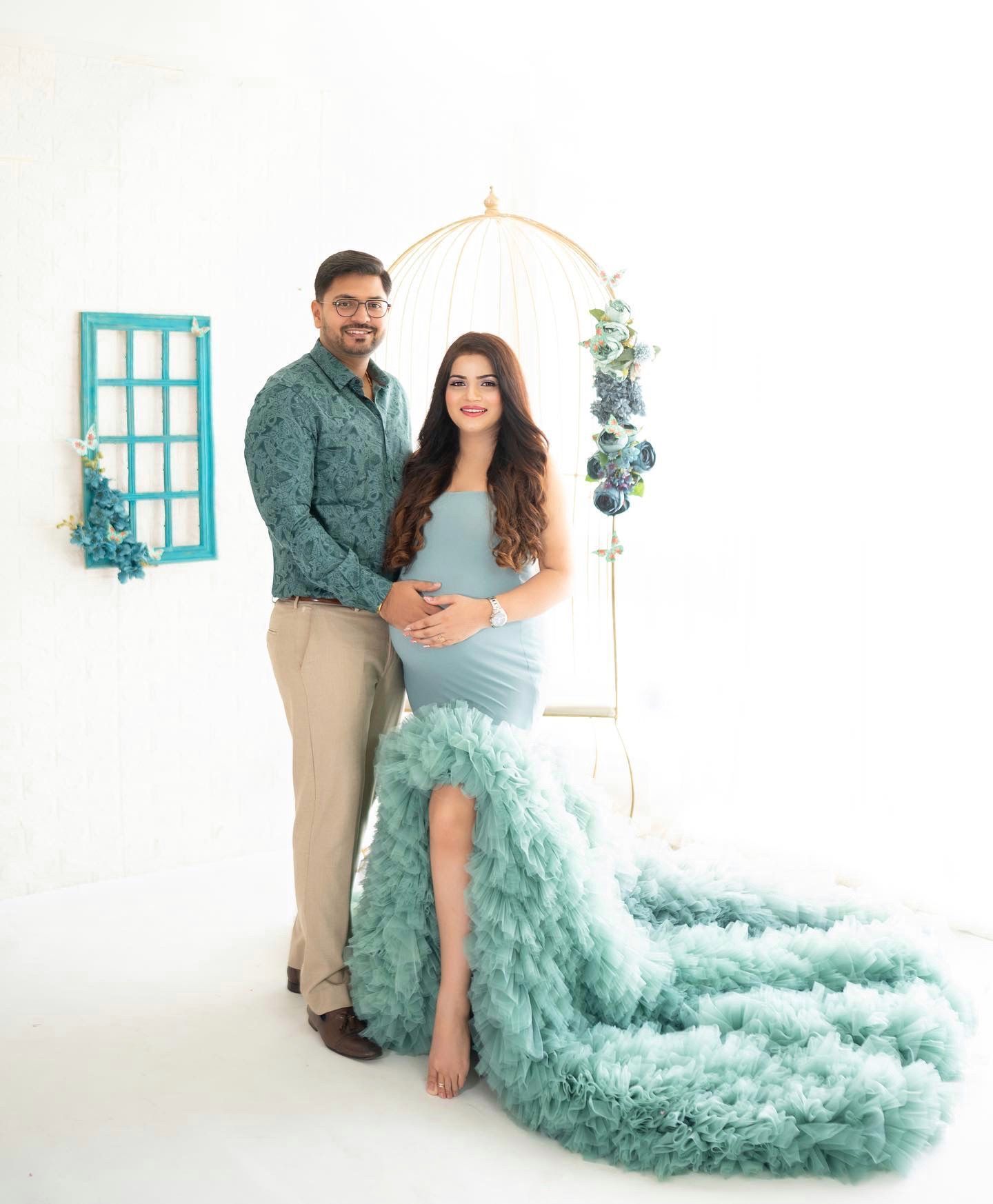 Dreamy maternity photos in a white studio with flowing mint green tulle gown.