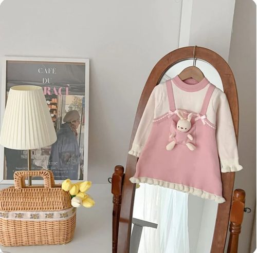 Pink and white dress outfit with bunny plush detail displayed on vintage mirror.