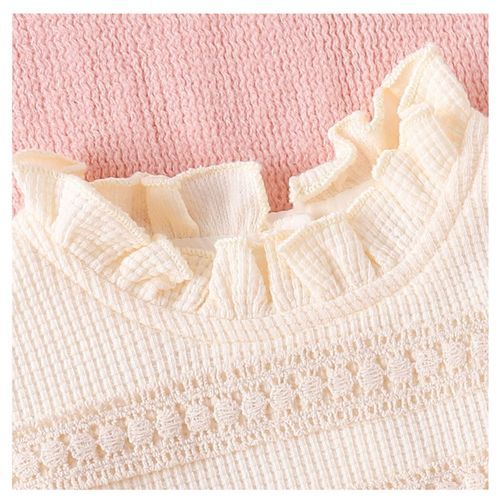 Close-up of cream colored ruffle trim with delicate textured knit pattern.