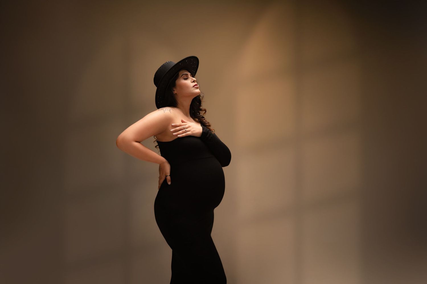 Dramatic silhouette maternity portraits with dark background and artistic lighting.