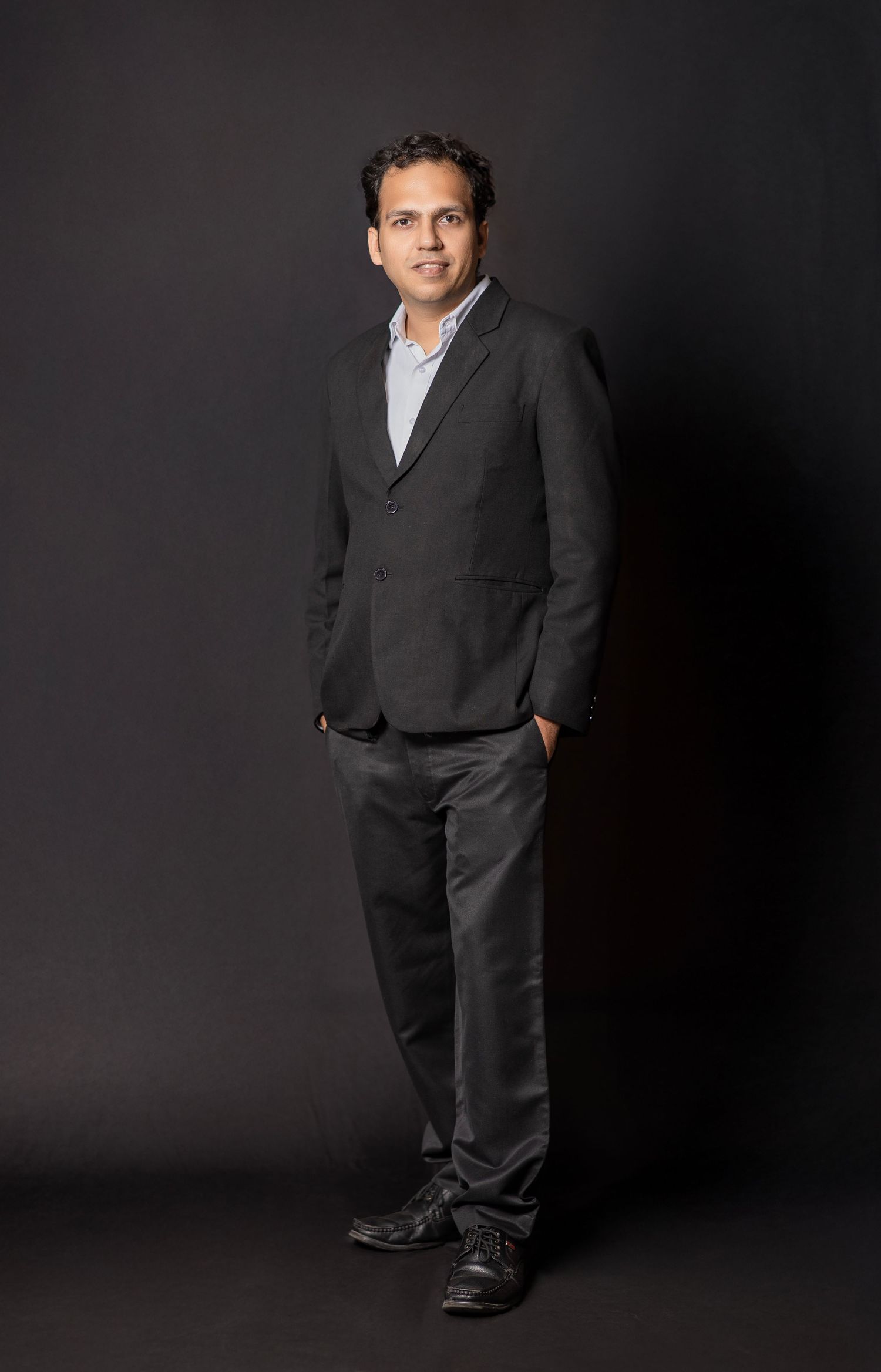 Professional studio portrait of a person wearing a dark business suit against a black background in four different poses.