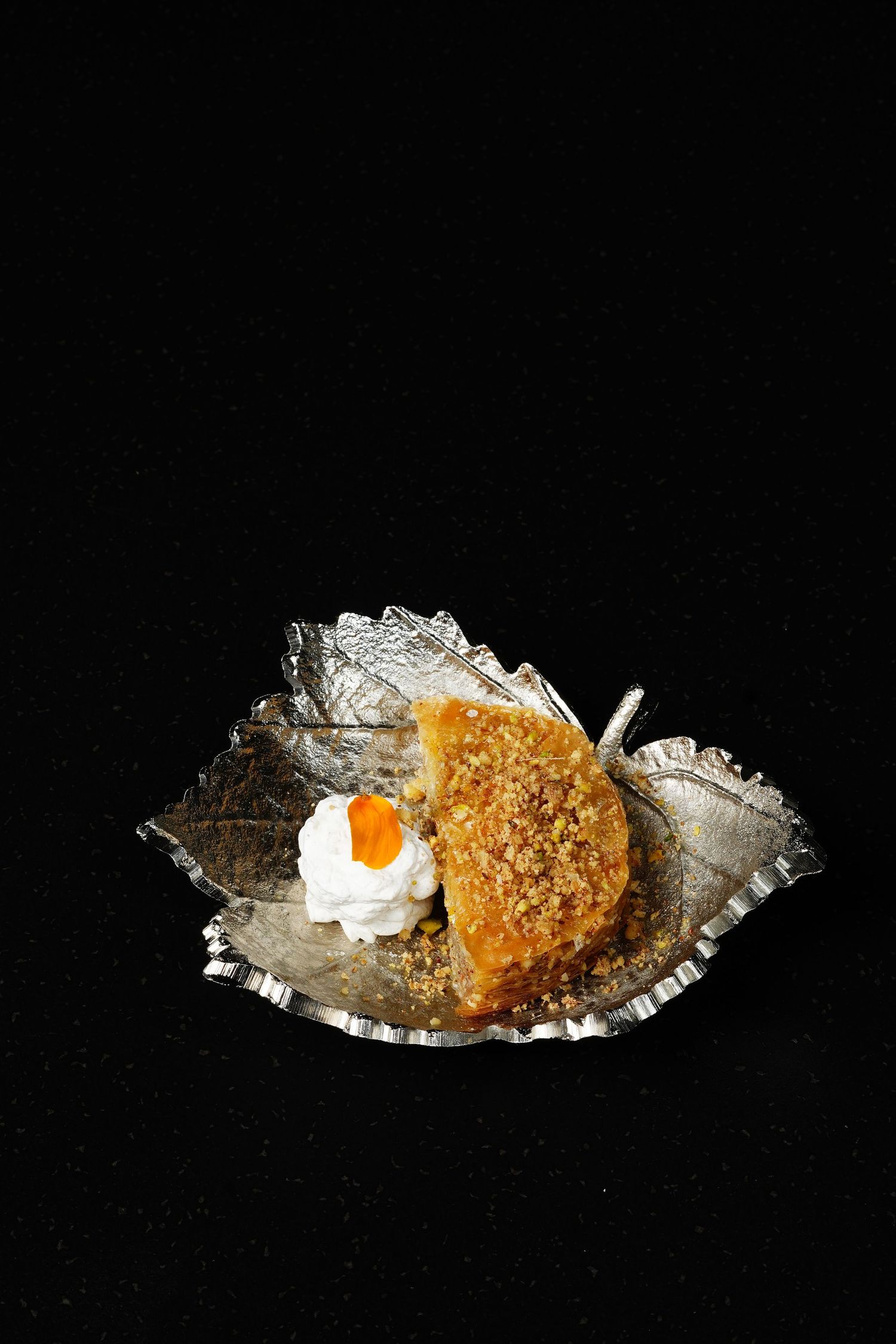 Four sequential photos showing a piece of breaded fish with garnish on a decorative silver plate against a black background.