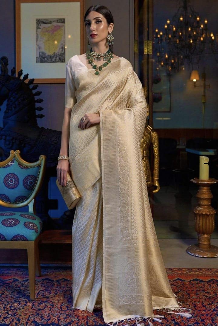 Luxurious cream banarasi silk saree styled with traditional emerald and pearl jewelry.