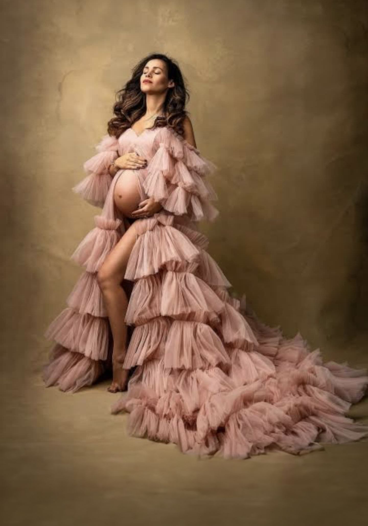 Studio maternity portraits showcasing a luxurious pink ruffled gown with dramatic train.