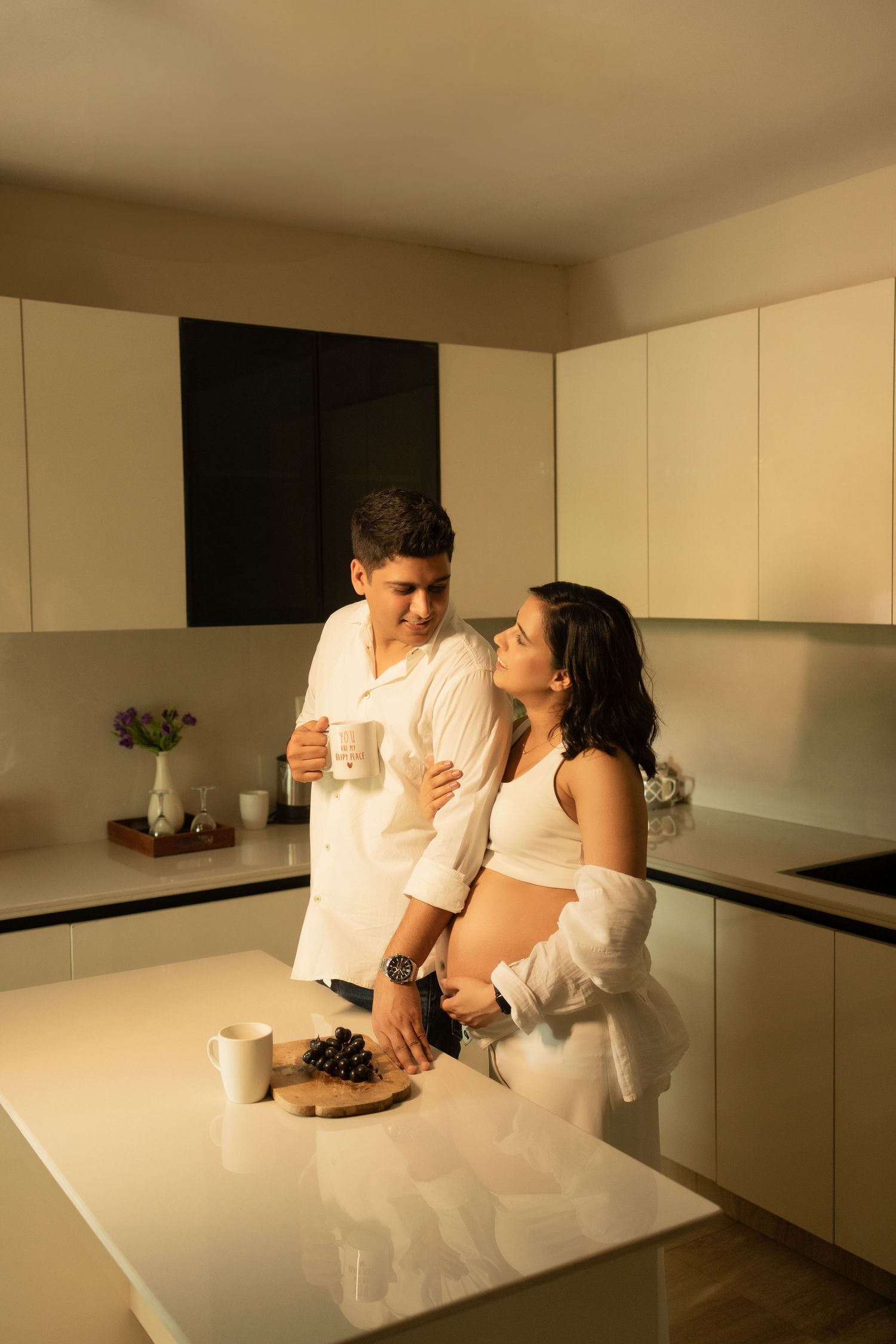 Romantic scene between two people in a minimalist kitchen space for maternity photoshoot.