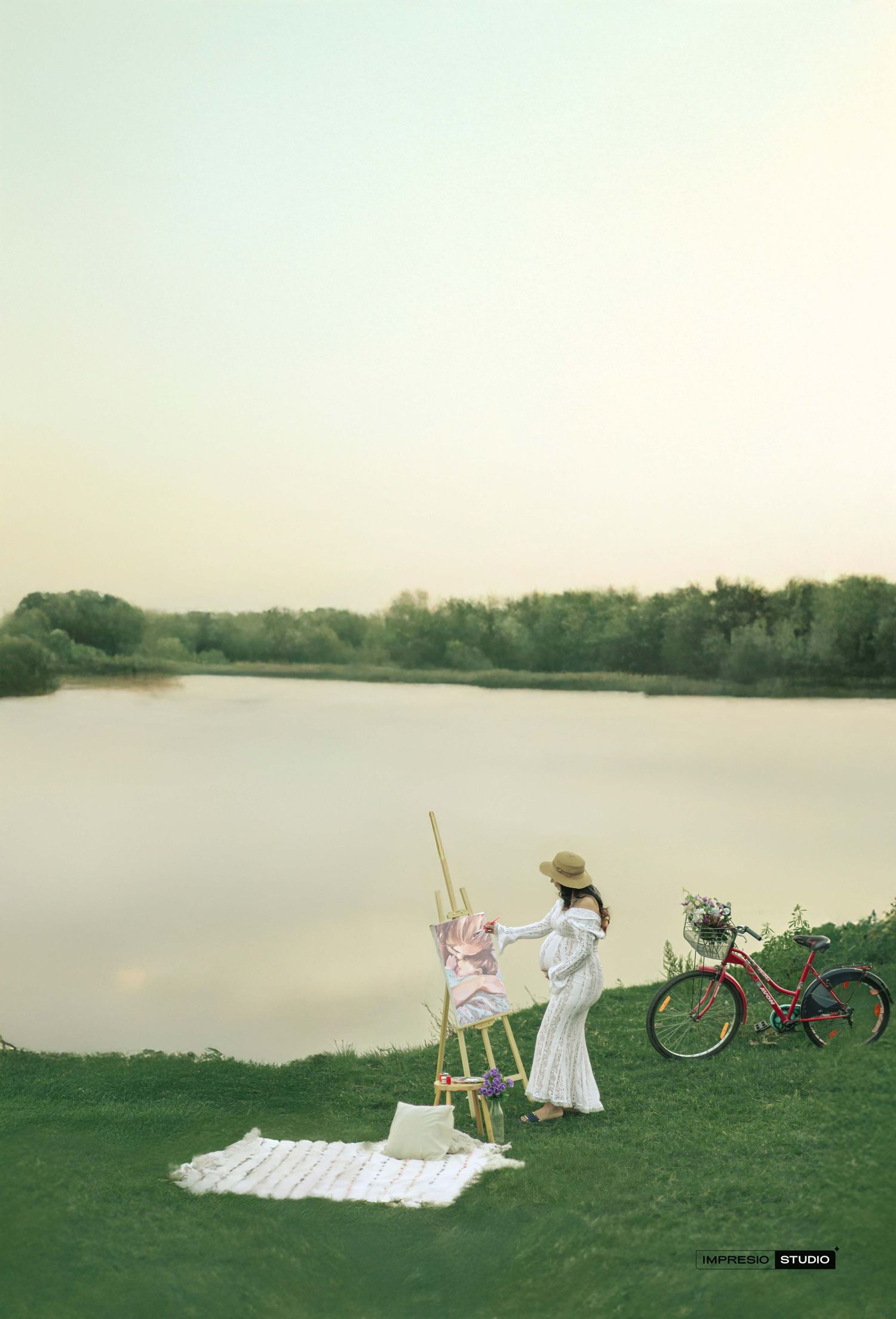 Artist painting on canvas by a serene lake at dusk, with a red bicycle nearby on lush green grass.