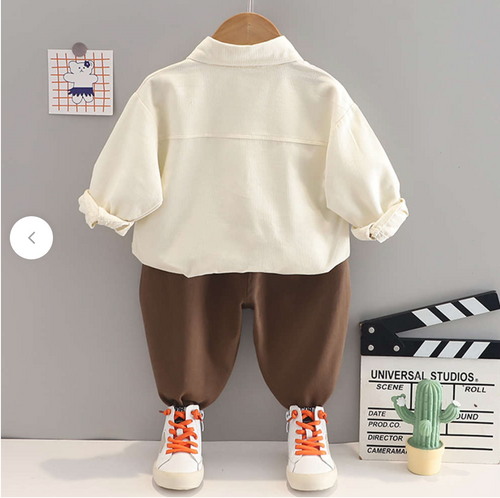 Baby outfit set with brown pants and white top displayed on wooden hangers.