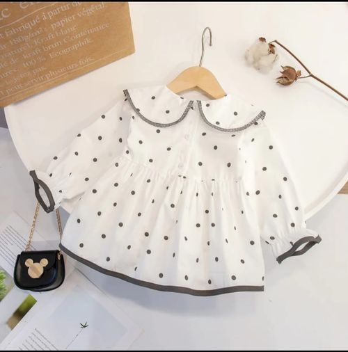 White polka dot baby dresses with Peter Pan collars on display.