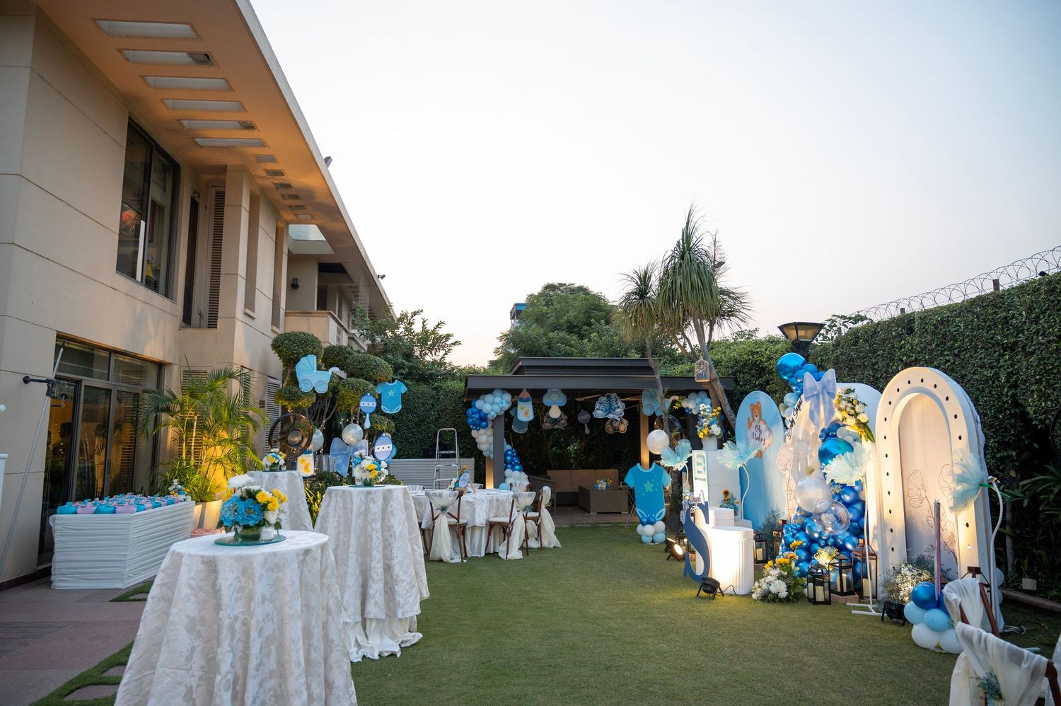 Outdoor event venue decorated with blue and white balloons and table settings.