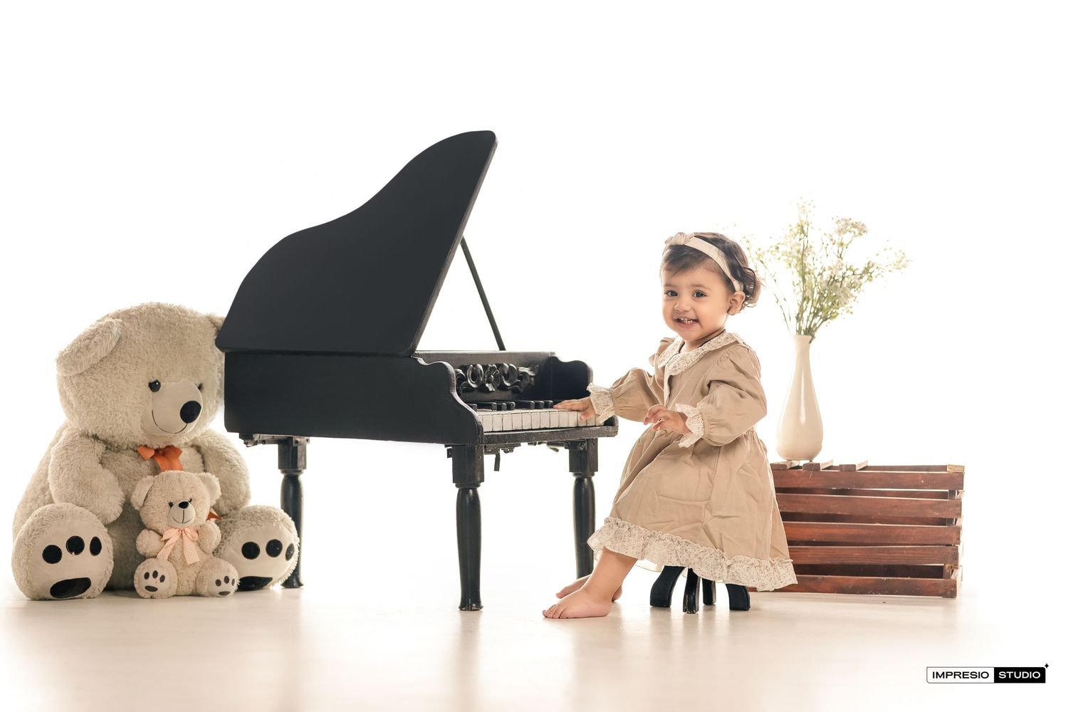 A row of teddy bears sitting near a piano arranged in ascending size order from small to large.