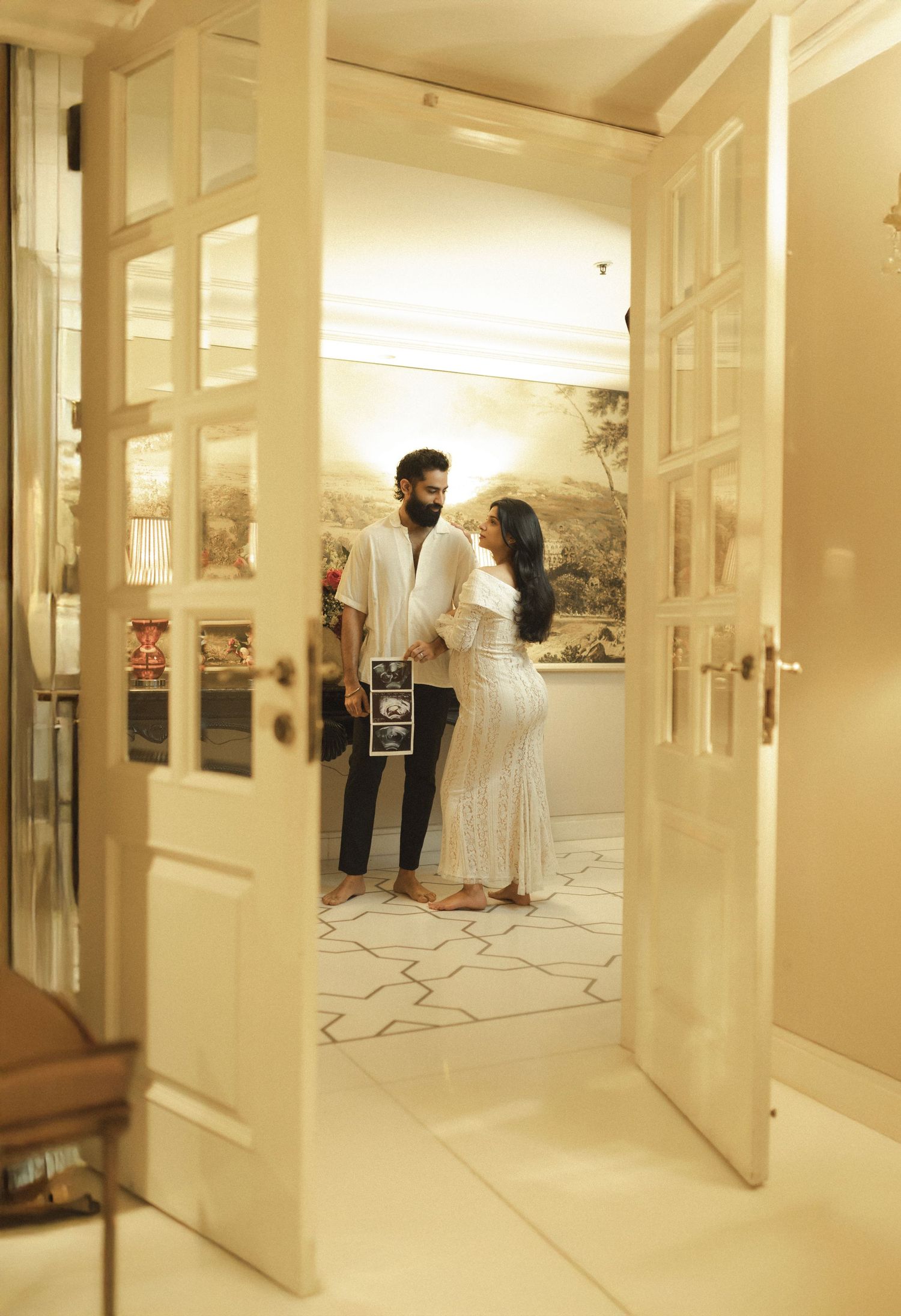 Interior view of bright white hallway with black decorative mannequins and artwork displayed along corridor walls.