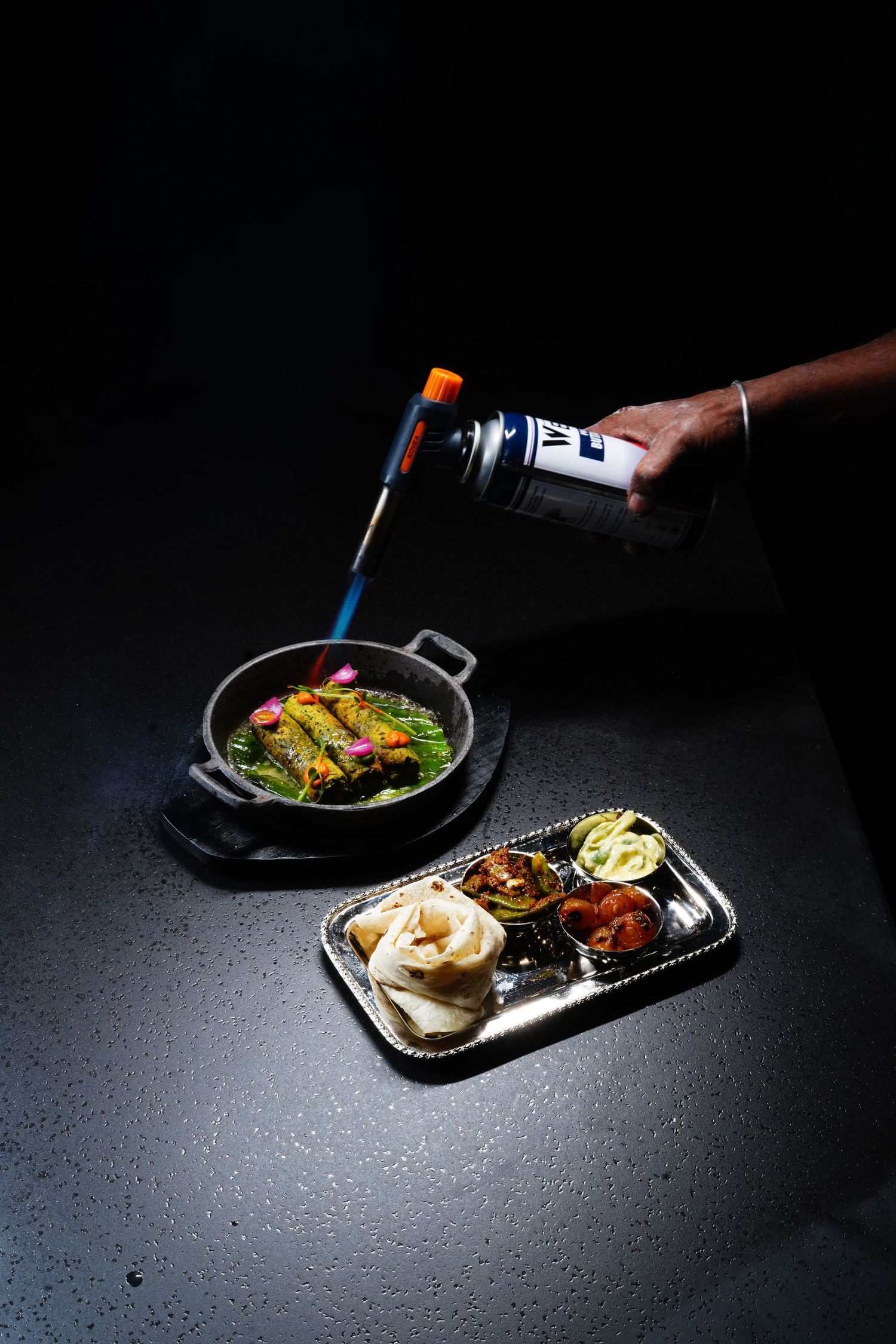 A series of dark and moody food photography shots showing various Asian dishes on black plates with dramatic lighting.