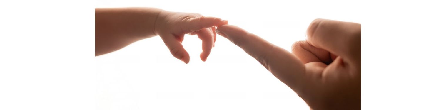 A baby's tiny hand gently touching an adult's finger against a white background.