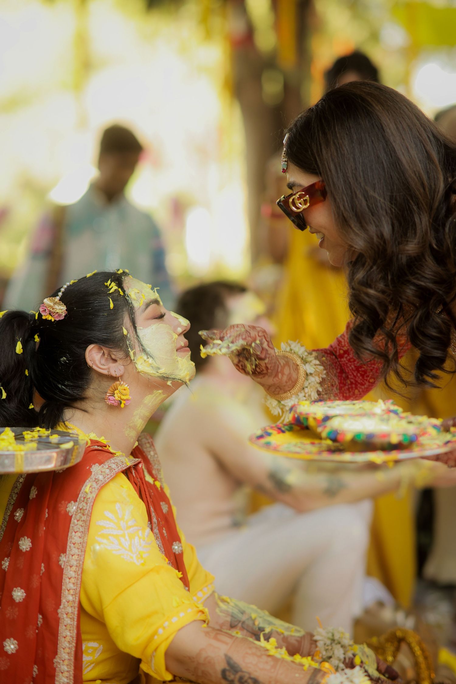 Colorful butterflies flutter around during a festive photoshoot featuring bright yellow and red traditional attire.