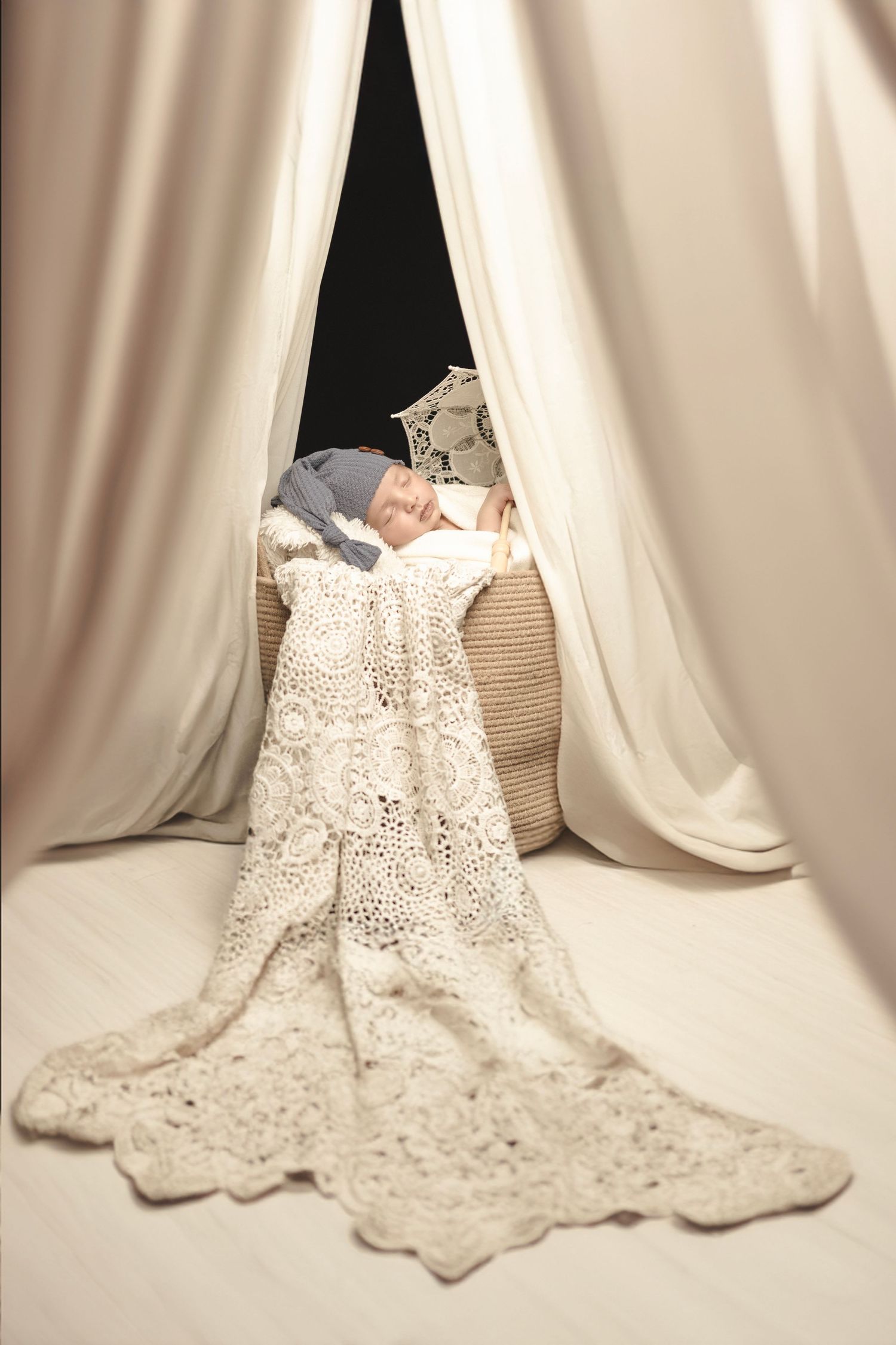 Delicate white lace fabric with intricate floral patterns cascades gracefully against a cream-colored backdrop.