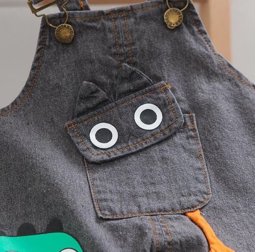 Denim overalls with playful googly eyes decorative detail on front pocket.