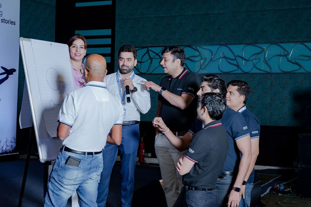 Group of professionals engaged in discussion at a corporate event near a presentation board in a modern venue.